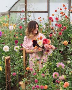 a woman standing in a garden with lots of flowers