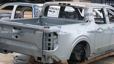 the rear end of a silver truck on a pallet in front of other vehicles