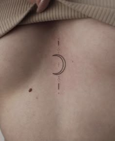 a woman's back with a crescent tattoo on her left side and the moon above it