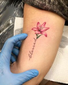 a person with a tattoo on their arm holding a pink flower and the word love written in cursive writing