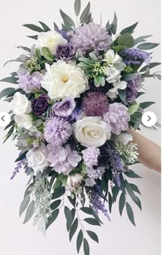 a bridal bouquet with purple and white flowers on display in front of the camera