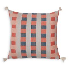 an orange and blue striped pillow with tassels on the sides, sitting against a white background