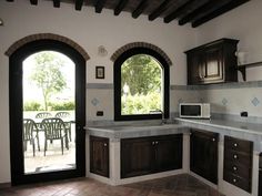 a kitchen with wooden cabinets and tile flooring next to an open door that leads to a patio