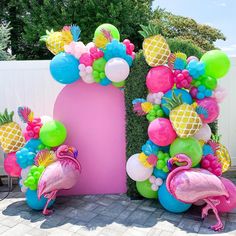 a pink letter decorated with pineapples, flamingos and balloons