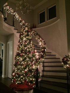 the christmas tree is decorated with red and white lights, while the stairs are lit up