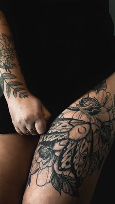 a woman's legs with tattoos on them and flowers in the middle of her leg