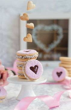 a table topped with donuts covered in frosting and heart shaped sugars next to pink ribbons