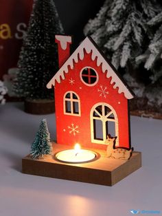 a lit candle in front of a small house