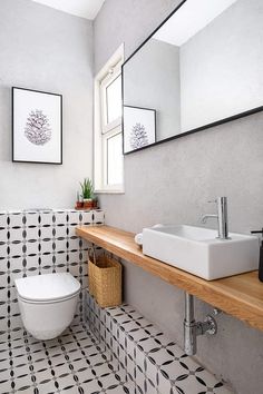 a white toilet sitting next to a sink in a bathroom under a mirror above a wooden counter