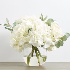 a vase filled with white flowers on top of a wooden table