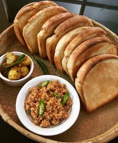 bread and other food items are arranged on a woven tray, along with small bowls