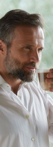 a man drinking from a glass in front of a window