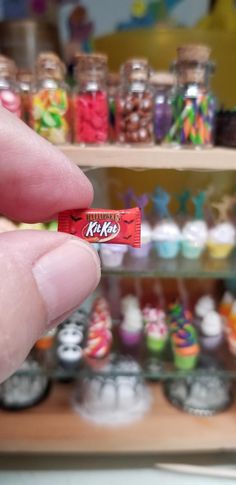 a hand holding a candy bar in front of a shelf full of cupcakes