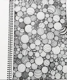 a spiral notebook with some black and white circles on the cover, next to a red pen