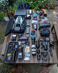 the table is covered with many different types of cameras and accessories, including an umbrella