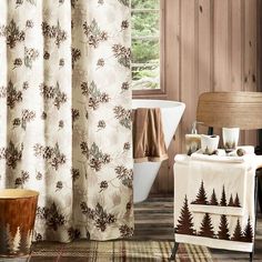 a bathroom with a bathtub, sink and shower curtain that has pine trees on it