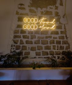 a brick wall with a neon sign that reads good food is good