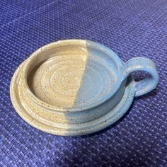 a blue and white dish sitting on top of a purple tablecloth next to a cup