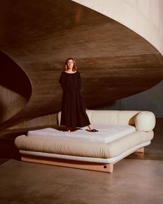 a woman standing on top of a bed next to a white couch and ottomans