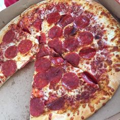 a pepperoni pizza in a box with one slice missing