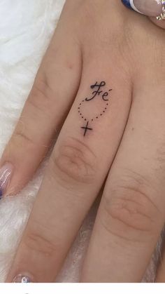 two fingers with tattoos on them, one has a cross and the other has an arrow