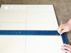 someone using a ruler to measure the top of a piece of paper on the floor