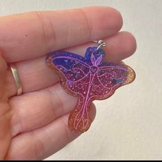 a hand holding a purple and pink butterfly shaped keychain