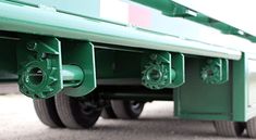 the rear end of a large green truck with metal pipes on it's sides