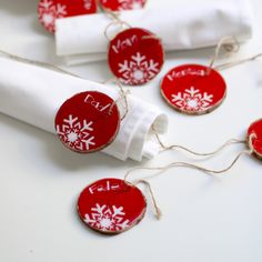 some red and white tags are hanging from twine on a napkin with snowflakes attached to them