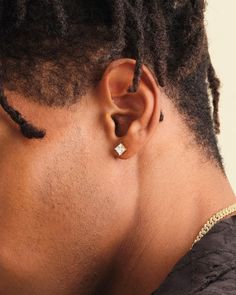 a man with dreadlocks wearing an earring in the shape of a cross