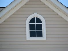 a window on the side of a house with a blue sky in the back ground