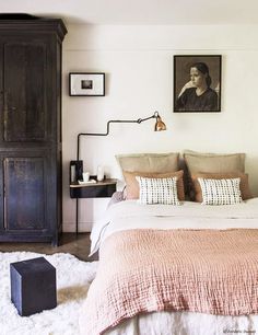 a bedroom with a bed, dresser and pictures hanging on the wall above it's headboard