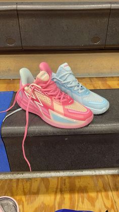 a pair of sneakers with pink and blue laces on top of a black box