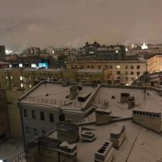 an aerial view of rooftops and buildings in the city at night with snow on them