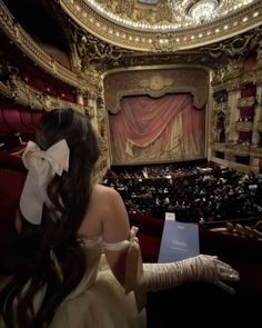 a woman in a white dress looking at an auditorium