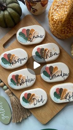 a wooden board topped with lots of cookies on top of a white table next to pumpkins