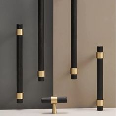 three black and gold poles are standing next to each other in front of a gray wall