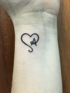 a small heart tattoo on the wrist with an arrow in the shape of a heart