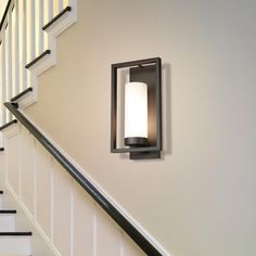 a light that is on the side of a stair case next to a banister