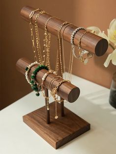 several necklaces are hanging on a wooden stand next to a vase with white flowers