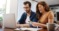 two people sitting at a table with a laptop and a credit card in front of them