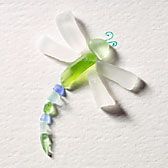 a green and white dragon brooch sitting on top of a wall