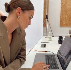 a woman sitting at a desk with a laptop computer in front of her, looking down