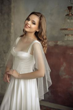 a woman in a white dress and veil posing for a photo with her hands on her hips