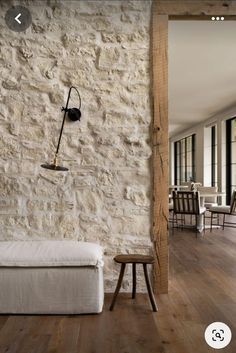 a white couch sitting in front of a stone wall next to a wooden table and chairs