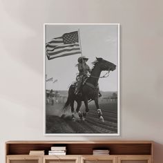 a black and white photo of a man on a horse holding an american flag in the background