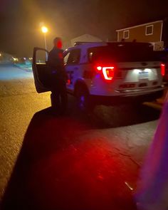 a man standing in the back of a white truck at night with its door open