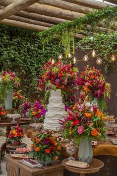 a table topped with lots of different types of flowers next to a wall covered in greenery