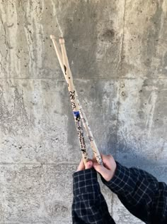 a person holding two wooden sticks in their hands