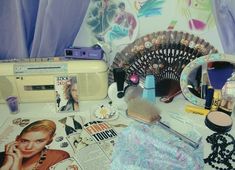 a table topped with lots of makeup and other items next to a fan on top of it